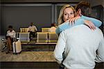 Happy couple hugging each other in waiting area at airport terminal