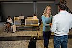 Happy couple holding hands while standing in waiting area at airport terminal