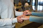 Mid-section of couple holding hands in waiting area at airport terminal