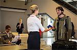 Man interacting with airport staff with luggage kept on conveyor belt at airport terminal