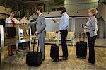 Female staff checking boarding pass of passengers at check-in counter in airport