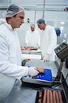 Butchers weighing packages of minced meat at meat factory