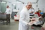 Portrait of butcher weighing packages of meat at meat factory