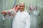 Portrait of butcher carrying raw meat at meat factory