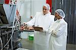 Technicians examining meat processing machine at meat factory