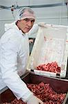 Portrait of butcher emptying minced meat in meat mincing machine at meat factory