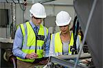 Technicians examining machine at meat factory