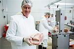 Portrait of butcher holding meat at meat factory