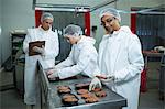 Butchers packaging hamburger patty at meat factory