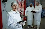 Portrait of female technician using digital tablet at meat factory