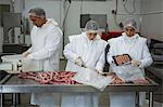 Butchers packing sausages at meat factory