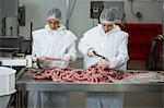 Female butchers cutting sausages at meat factory