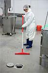 Female staff cleaning the floor at meat factory