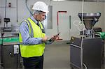 Attentive technician using digital tablet at meat factory