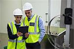 Two technician discussing over digital tablet at meat factory