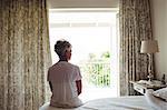 Senior woman sitting on a bed in bedroom at home