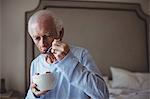 Senior man having breakfast in bedroom at home