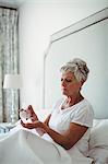 Senior woman taking medicine in bedroom at home