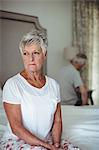 Worried and thoughtful senior woman sitting in bed room