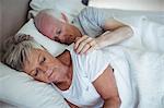 Senior couple sleeping on bed in bedroom