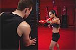 Female boxer practicing with trainer at fitness studio