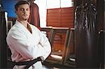 Karate player standing with arms crossed in fitness studio