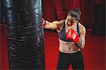 Female boxer punching a boxing bag in fitness studio