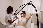 Doctor performing laser hair removal on female patient skin in clinic