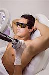 Doctor performing laser hair removal on male patient skin in clinic