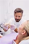 Dentist showing denture model to the patient in clinic