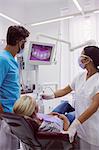 Male and female dentist examining patient in dental clinic