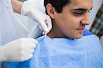 Dentist assisting a patient to wear dental apron at clinic