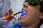 Dentist examining patients teeth with dental curing light at clinic