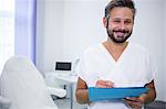 Portrait of smiling doctor writing on medical reports in clinic
