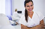 Portrait of smiling dentist standing with arms crossed at clinic