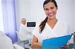 Portrait of smiling dentist writing a medical report in clinic