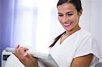 Smiling dentist using digital tablet in clinic