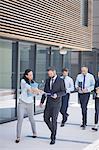 Group of confident business people walking outside office building