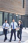 Confident businessman walking with colleagues outside office building