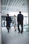Rear view of businesswoman walking with colleagues inside office building