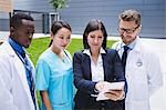 Team of doctors discussing over digital tablet in hospital premises