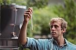 Man wearing apron checking temperature while making beer at home brewery