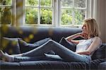 Thoughtful woman sitting on sofa in living room at home