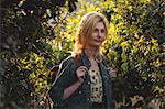 Thoughtful woman standing with bag in forest