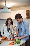 Couple cutting vegetables together in kitchen at home