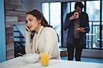 Woman talking on mobile phone while having breakfast at home