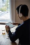 Man listening music on digital tablet at home