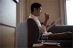 Man using digital tablet while having sandwich at home