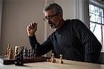 Attentive man playing chess at home