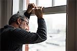 Thoughtful man looking through window at home